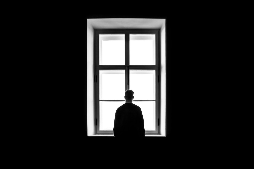 A person sitting alone in a crowd, representing modern loneliness despite digital connection